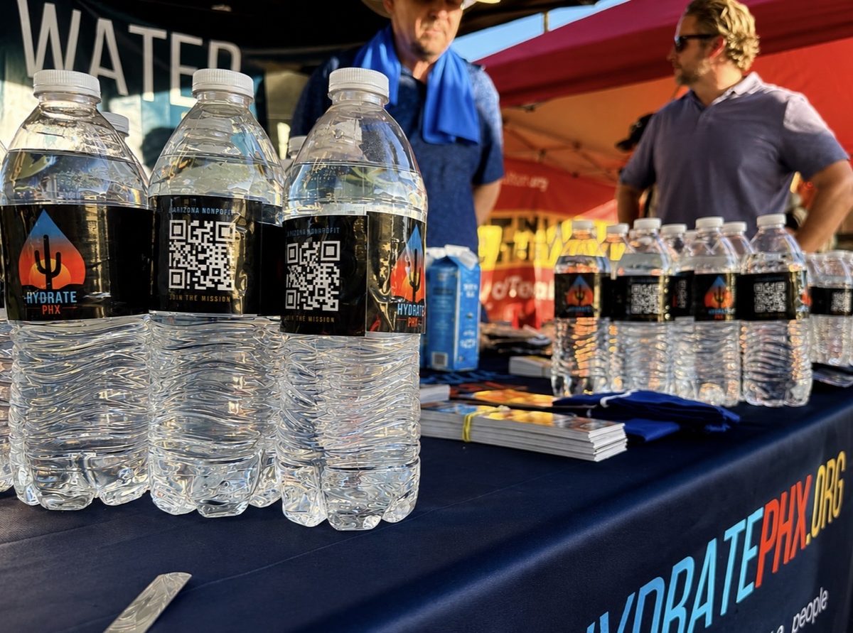 Hydrate PHX-labeled water bottles with QR codes on the distribution table.