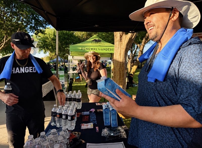 The Hydrate PHX team at the distribution booth holding shelf-stable water cartons.