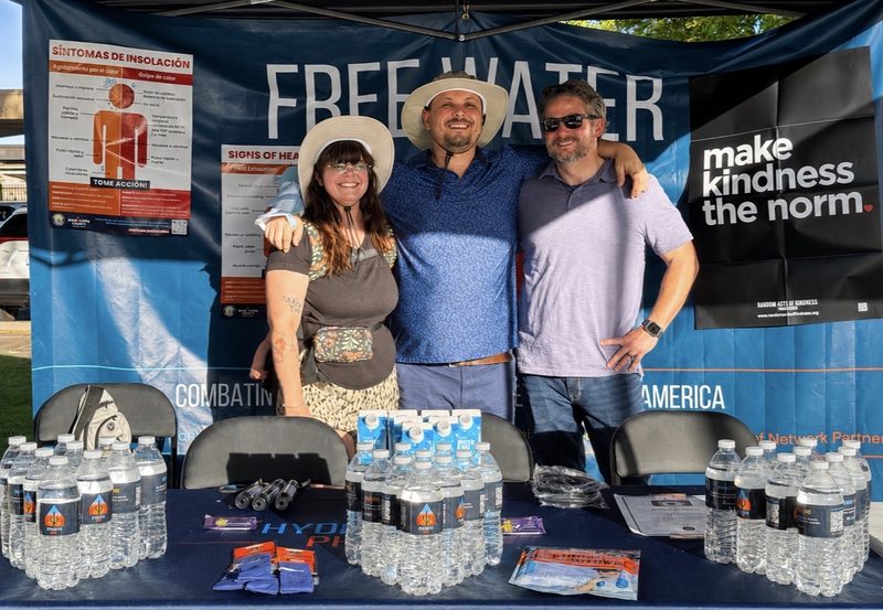 The Hydrate PHX volunteer team stands together behind the free water distribution booth.